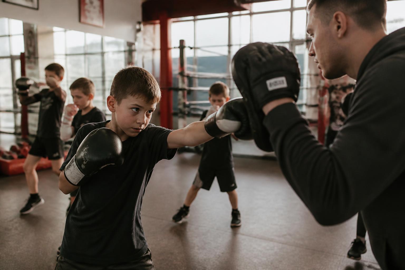 Young boxer working mitts with a TLAP365 coach in the gym